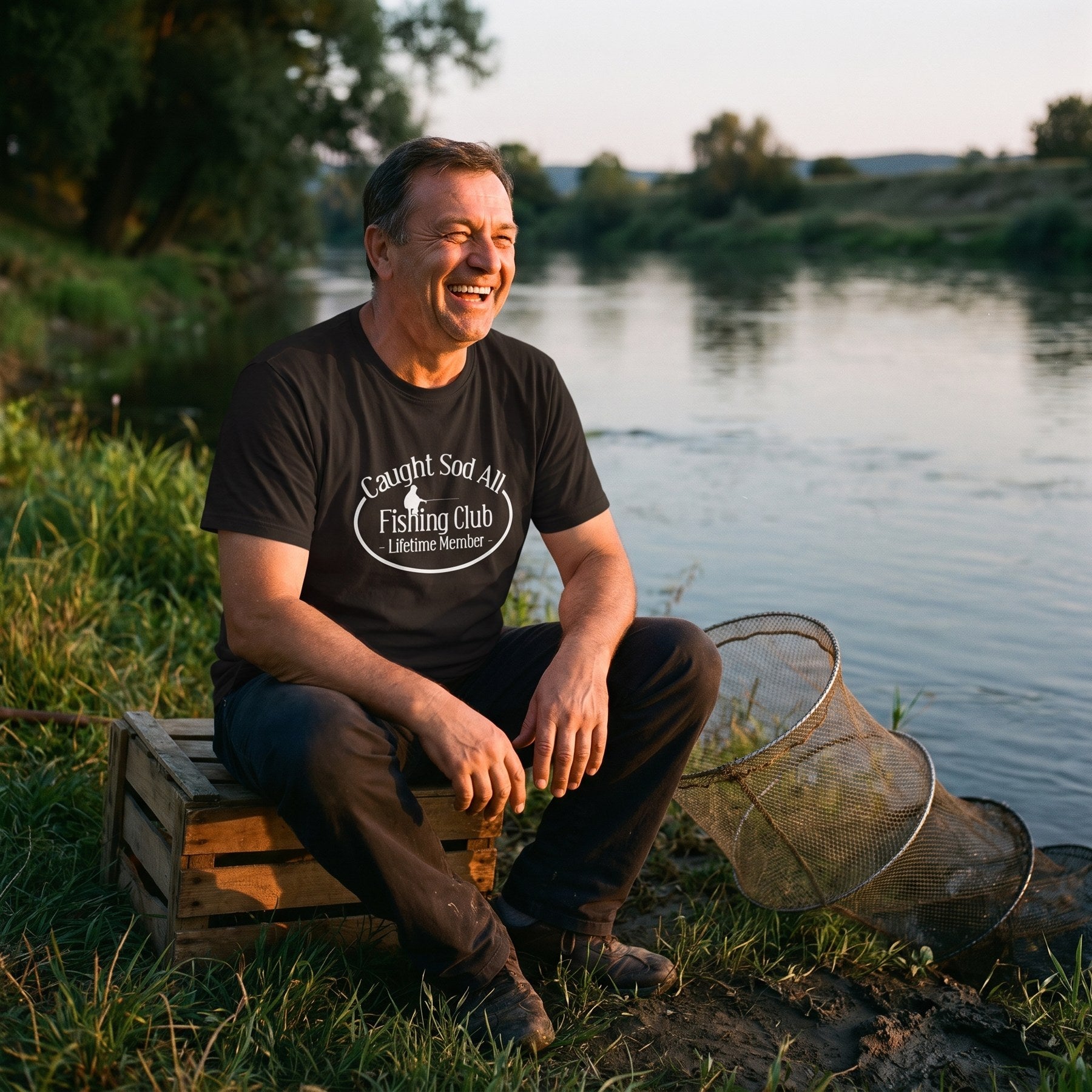 Angler sitting by the water wearing the Caught Sod All tee